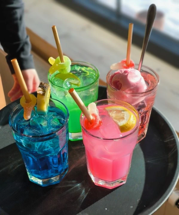 Fyra barndrinkar i blått, grönt, rosa och med glass på en bricka